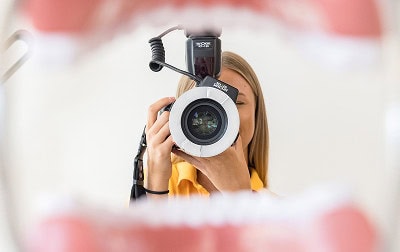 Fotografin macht Aufnahme durch offenen Mund, Fokus auf Kamera, kreative Perspektive in der Fotografie.