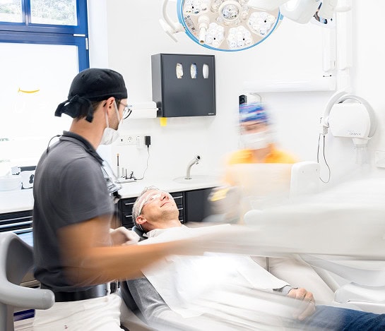 Zahnarzt behandelt lächelnden Patienten in moderner Zahnarztpraxis mit medizinischem Equipment.