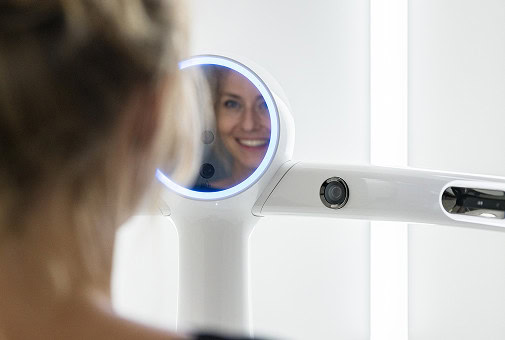 Futuristischer Spiegel reflektiert Frau mit Lächeln, umgeben von weißem, modernem Design.